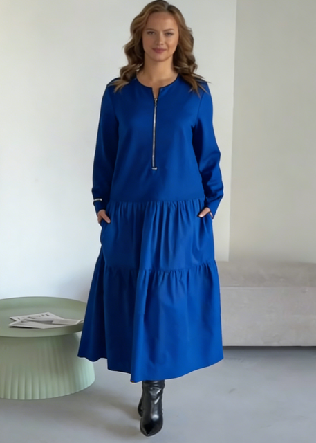 O vestido apresenta um decote com fecho, mangas compridas e uma saia plissada em camadas.