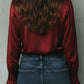 Uma elegante blusa de cetim cor de vinho com mangas largas e detalhes em renda