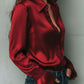 Uma elegante blusa de cetim cor de vinho com mangas largas e detalhes em renda