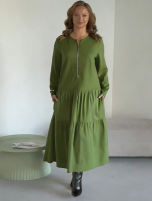 O vestido apresenta um decote com fecho, mangas compridas e uma saia plissada em camadas.