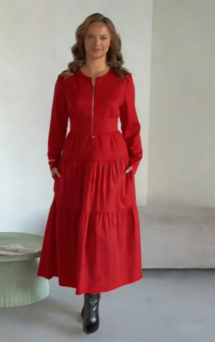 O vestido apresenta um decote com fecho, mangas compridas e uma saia plissada em camadas.