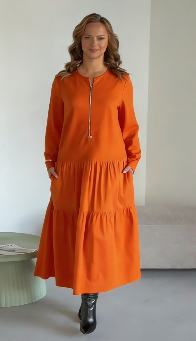 O vestido apresenta um decote com fecho, mangas compridas e uma saia plissada em camadas.
