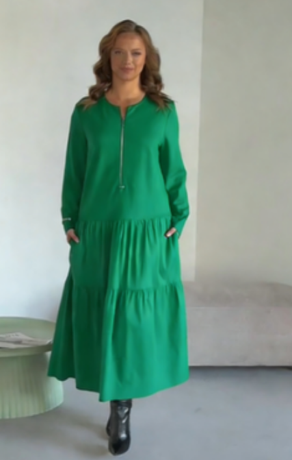 O vestido apresenta um decote com fecho, mangas compridas e uma saia plissada em camadas.
